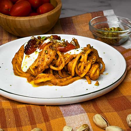 Pici in crema di pomodorini confit, stracciatella e pistacchi